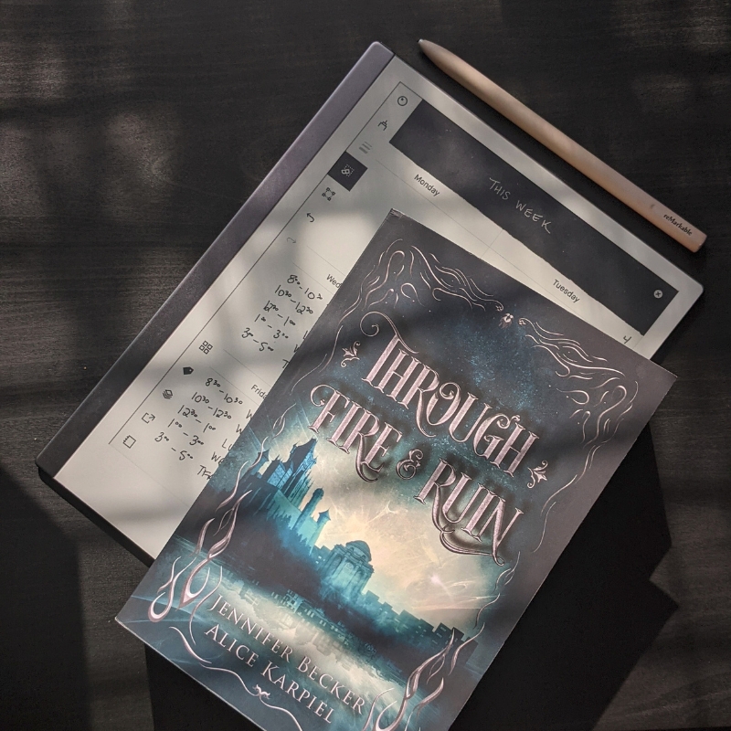 Book 'Through Fire and Ruin' on top of writing tablet on black background